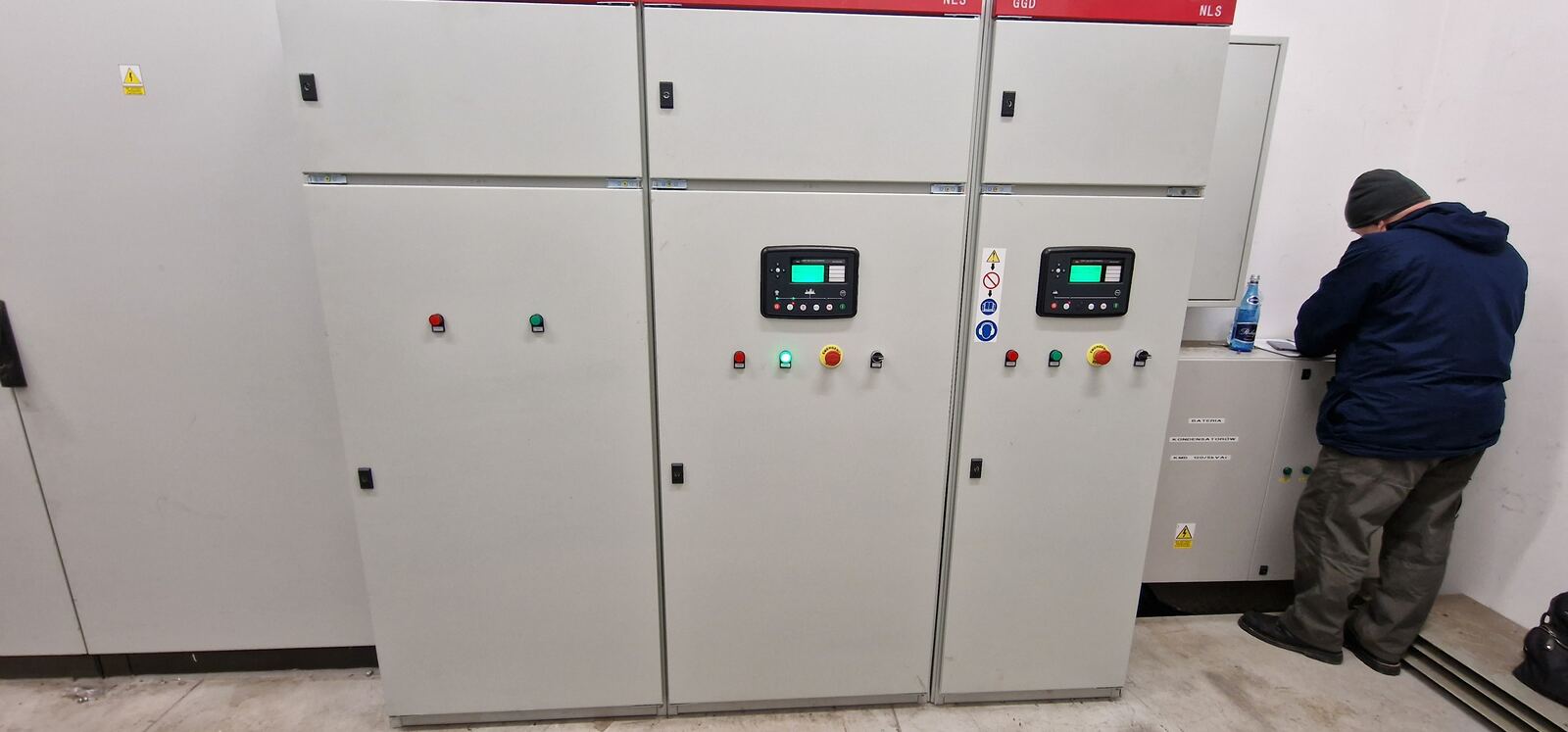 Rozdzielnica z układem SZR i sterownikami, technik podczas prac